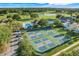 Aerial view of community featuring a pool, tennis courts, and lush landscaping near the golf course and pond at 9081 Saint Andrews Way, Mount Dora, FL 32757