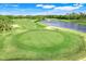 Scenic view of a lush green golf course with a pond, sand traps, and a pristine putting green at 9081 Saint Andrews Way, Mount Dora, FL 32757