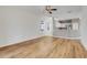 Spacious living room with light hardwood flooring, ceiling fan, and views into kitchen area at 9081 Saint Andrews Way, Mount Dora, FL 32757
