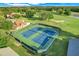 Aerial view of well-maintained tennis courts with green surroundings and a beautiful clubhouse nearby at 9081 Saint Andrews Way, Mount Dora, FL 32757