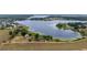 Expansive aerial view of a lakefront property with a home, barn, and verdant landscape extending to the water's edge at 9510 Suggs Rd, Clermont, FL 34711