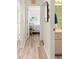 Hallway leads to a bedroom and bathroom, featuring wood-look floors, neutral paint, and beach-themed decor at 9645 Se 173Rd Pl, Summerfield, FL 34491