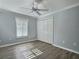 Bedroom with wood-look floors, white trim, and a ceiling fan for added comfort at 997 Oscar Ln, The Villages, FL 32162