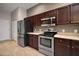 Well-equipped kitchen with stainless steel appliances and dark wood cabinets at 10021 Lake Miona Way, Oxford, FL 34484
