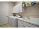 Practical laundry room equipped with washer, dryer, utility sink, and ample cabinet space at 10021 Lake Miona Way, Oxford, FL 34484
