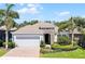 Charming single-story home with a manicured lawn, brick driveway, and a two-car garage surrounded by lush landscaping at 1047 Timbervale Trl, Clermont, FL 34715