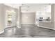 Spacious living room with gray wood-look floors connects to the kitchen with white cabinets and stainless appliances at 11780 Se 178Th St, Summerfield, FL 34491