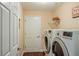 Laundry room features modern washer and dryer units with wood look flooring and bright paint at 1222 Camero Dr, The Villages, FL 32159