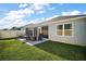 Wide backyard featuring a concrete patio, green grass, and a tall white fence at 1251 Saranac Pl, The Villages, FL 32163