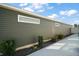 Landscaped side yard featuring modern horizontal siding, decorative rock, and lush greenery at 1251 Saranac Pl, The Villages, FL 32163
