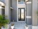 Stunning front door with decorative glass, flanked by columns and lush tropical plants at 13519 Bristlecone Cir, Orlando, FL 32828