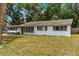 Exterior shot showcasing the home, mature trees, and long driveway leading to the covered parking area at 1406 Spartan Ave, Leesburg, FL 34748