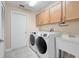 Bright laundry room with washer, dryer, sink, white appliances and tile floor at 14305 Pine Cone Trl, Clermont, FL 34711