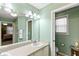 Bathroom featuring double sinks, green walls, a large mirror, and a toilet with a window at 1526 Blueberry Way, The Villages, FL 32162