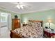 Bedroom with green walls, floral bedspread, and classic furniture; adjoining bathroom visible at 1526 Blueberry Way, The Villages, FL 32162