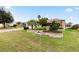 Landscaped front yard features a stone-lined flower bed, palm tree, and beautiful greenery at 1526 Blueberry Way, The Villages, FL 32162