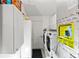 Laundry room with washer, dryer, and storage cabinets; features AC and laundry supplies at 1526 Blueberry Way, The Villages, FL 32162