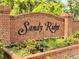 Brick sign with 'Sandy Ridge' in script, surrounded by well-maintained landscaping at community entrance at 156 Ridgebrook Ct, Davenport, FL 33896