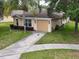 Single-story home with a tan exterior, green lawn, and a paved driveway at 156 Ridgebrook Ct, Davenport, FL 33896
