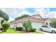 Side exterior featuring manicured lawn, attached two-car garage and mature cactus at 15702 Bay Vista Dr, Clermont, FL 34714