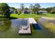 Wide aerial shot capturing a dock with a covered area, connecting to a home amidst expansive greenery at 16047 E Shirley Shores Rd, Tavares, FL 32778