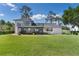 Beautiful backyard view with a modern white house, manicured lawn, a screened in patio, and upper level deck at 16047 E Shirley Shores Rd, Tavares, FL 32778