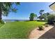 Large backyard overlooking the serene lake with a dock, mature trees, and beautifully landscaped lawn at 16047 E Shirley Shores Rd, Tavares, FL 32778