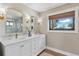 Elegant bathroom featuring a double vanity, gold accents, and a window with natural light at 16047 E Shirley Shores Rd, Tavares, FL 32778