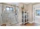 Modern bathroom showcasing a glass-enclosed shower, marble tiles, and stylish storage at 16047 E Shirley Shores Rd, Tavares, FL 32778