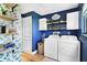 Charming laundry room with blue walls, cabinets, shelves, and modern washer and dryer at 16047 E Shirley Shores Rd, Tavares, FL 32778