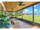 A screened porch with a view of the lake and seating area featuring wicker furniture and a wooden ceiling at 16047 E Shirley Shores Rd, Tavares, FL 32778
