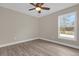 Well lit bedroom with hardwood flooring, a ceiling fan, and a window with a view at 16380 Se 83Rd Ct, Summerfield, FL 34491
