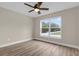 Well lit bedroom with hardwood flooring, a ceiling fan, and a window with a view at 16380 Se 83Rd Ct, Summerfield, FL 34491