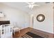 Cozy room featuring wood floors, a ceiling fan, white chair, and round mirror at 1716 Bugle Ter, The Villages, FL 32162
