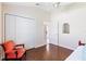 Bright bedroom featuring wood flooring, an orange accent chair, and closet access at 1716 Bugle Ter, The Villages, FL 32162