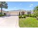 Well-maintained single-story home with manicured lawn, mature palms, and a triple-car garage at 1716 Bugle Ter, The Villages, FL 32162