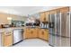 Open-concept kitchen with stainless steel appliances and bar seating overlooks the living area at 1716 Bugle Ter, The Villages, FL 32162