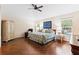 Comfortable main bedroom with a floral-patterned bed, wood floors, and bright, airy windows at 1716 Bugle Ter, The Villages, FL 32162