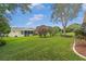 Spacious backyard with well-maintained lawn, mature trees, bushes, and a screened in patio at 17806 Se 97Th Ct, Summerfield, FL 34491