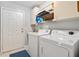 Well lit laundry room with a front loading washer and dryer and overhead storage at 17806 Se 97Th Ct, Summerfield, FL 34491