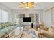 Bright living room features a ceiling fan, a sofa and a glass coffee table on a blue rug at 17806 Se 97Th Ct, Summerfield, FL 34491