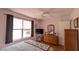 Cozy bedroom featuring hardwood floors, a window, a ceiling fan, and a dresser with mirror at 17930 Se 83Rd Melody Ave, The Villages, FL 32162