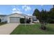 Cozy home with a well-manicured front yard, showcasing a tidy lawn and an attached garage at 17930 Se 83Rd Melody Ave, The Villages, FL 32162