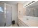Well-lit bathroom with a glass-enclosed shower, vanity, and storage cabinet at 17985 Se 102Nd Ct, Summerfield, FL 34491