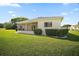Rear exterior showcasing a sunroom, green lawn, and manicured hedges at 17985 Se 102Nd Ct, Summerfield, FL 34491