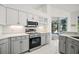 Kitchen with stainless steel appliances, stylish gray cabinetry, quartz countertops, and backyard pool access at 1860 Park Forest Blvd, Mount Dora, FL 32757
