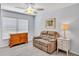 Cozy bedroom featuring a loveseat, ceiling fan, and a dresser with ample storage space at 1871 W Schwartz Blvd, Lady Lake, FL 32159