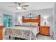 Primary bedroom features stylish headboard, ceiling fan, bedside lamps, and window overlooking the backyard at 1871 W Schwartz Blvd, Lady Lake, FL 32159