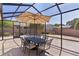 Enclosed lanai featuring a dining table with sun umbrella overlooking a well-manicured lawn at 2026 Altamonte Way, The Villages, FL 32162