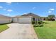 Charming single-story home with a two-car garage, well-maintained lawn, and beautiful landscaping at 2104 Iveywood St, The Villages, FL 32163